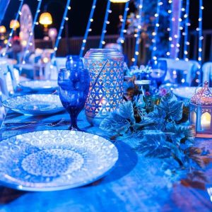 Midnight blue candle light dinner decoration with deep blue theme, candles, elegant table setup, and ambient lighting