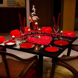 Newlywed candle light dinner decoration with romantic setup, candles, rose petals, elegant table décor, and warm ambient lighting